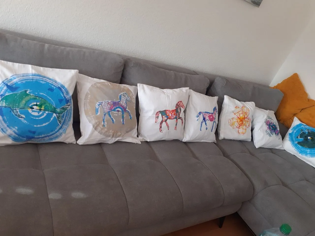 Selbst bemalte Kissen mit Pferde- und Spiralmotiven auf einem Sofa