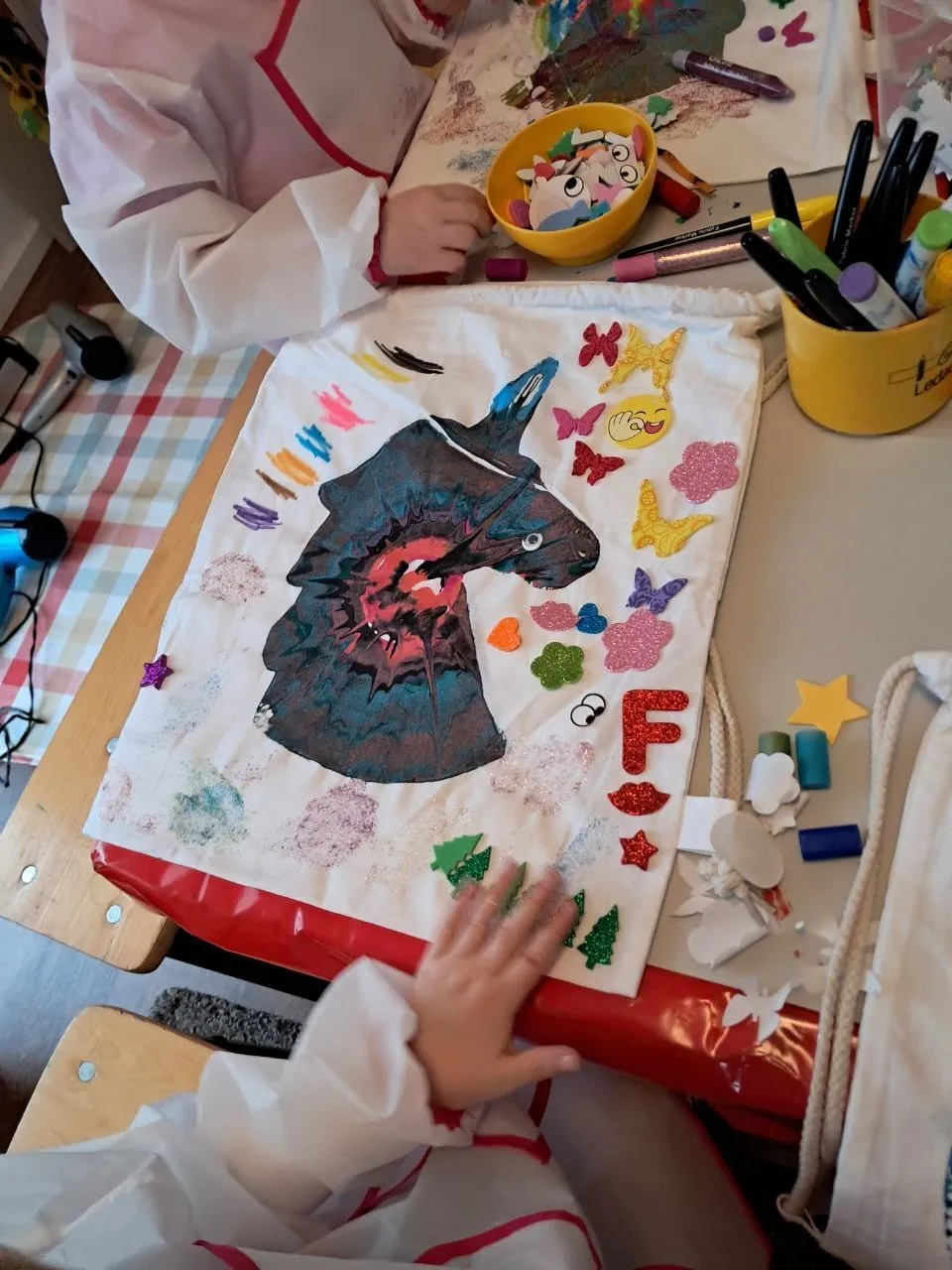 Kinderhände bemalen einen Stoffbeutel mit Einhorn-Motiv