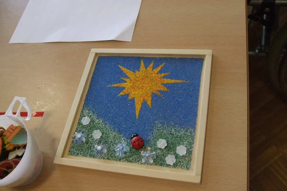 Mosaikbild mit Sonne und Wiese im Holzrahmen