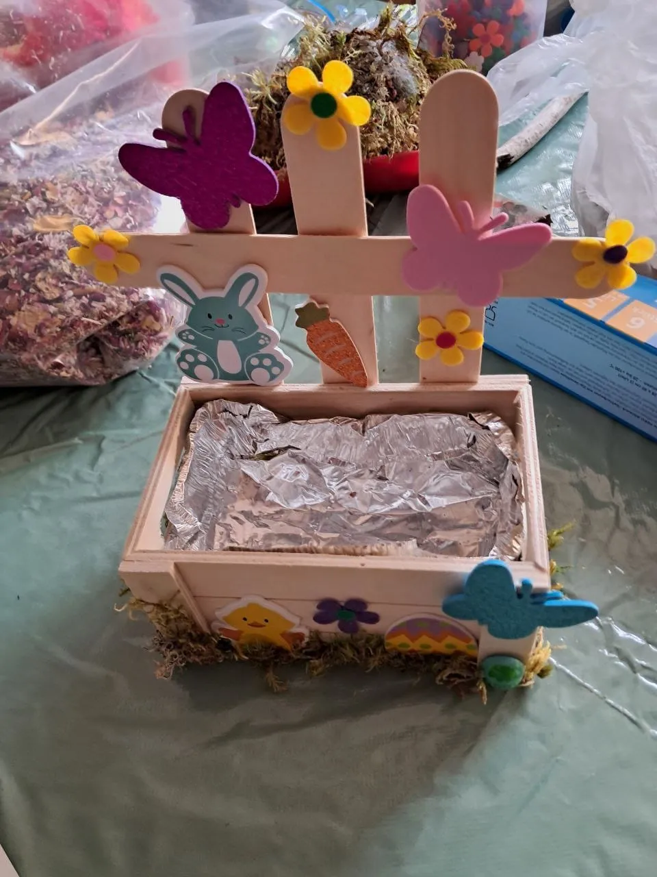 Holzkreuz mit Schmetterlingen und Blumen auf einem Holzkästchen