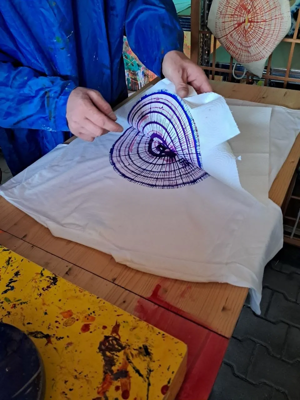 Ein Kind gestaltet ein T-Shirt mit lila Spiralmuster