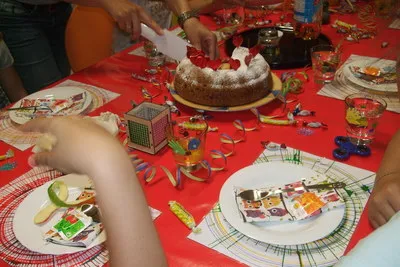 Gedeckter Geburtstagstisch mit Kuchen, bunten Tellern und Luftschlangen